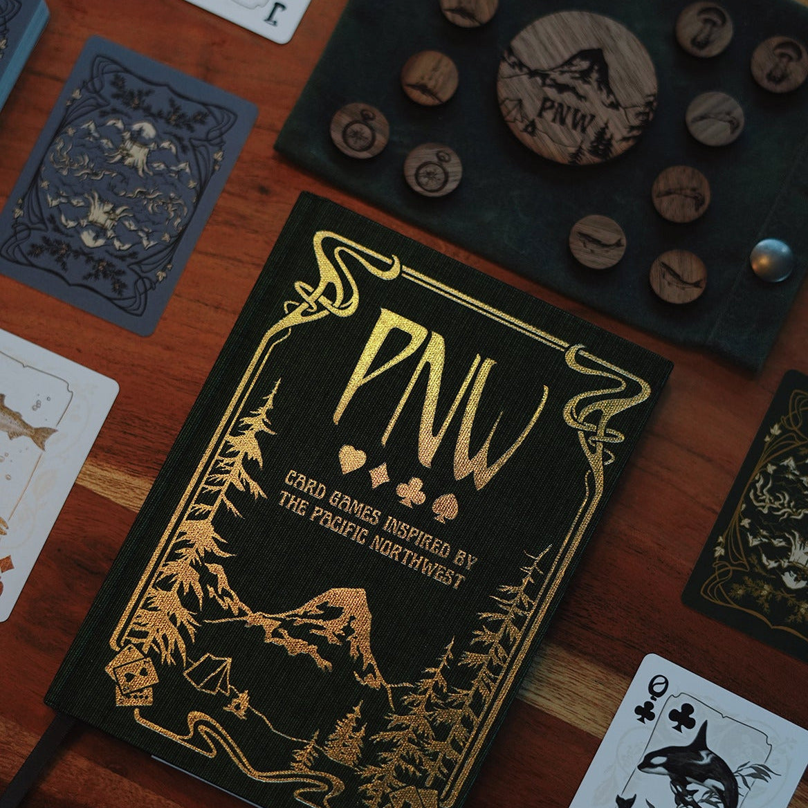 Card game box with 'PNW' branding on a wooden surface with cards and wooden tokens.